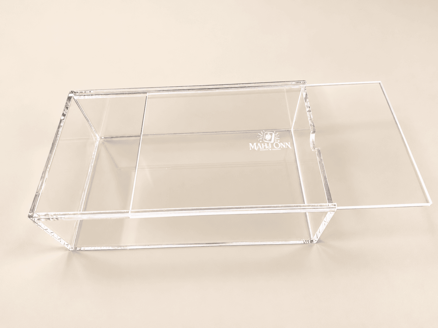Clear Mahj-Onn acrylic tile storage box with its sliding lid open and a small printed logo